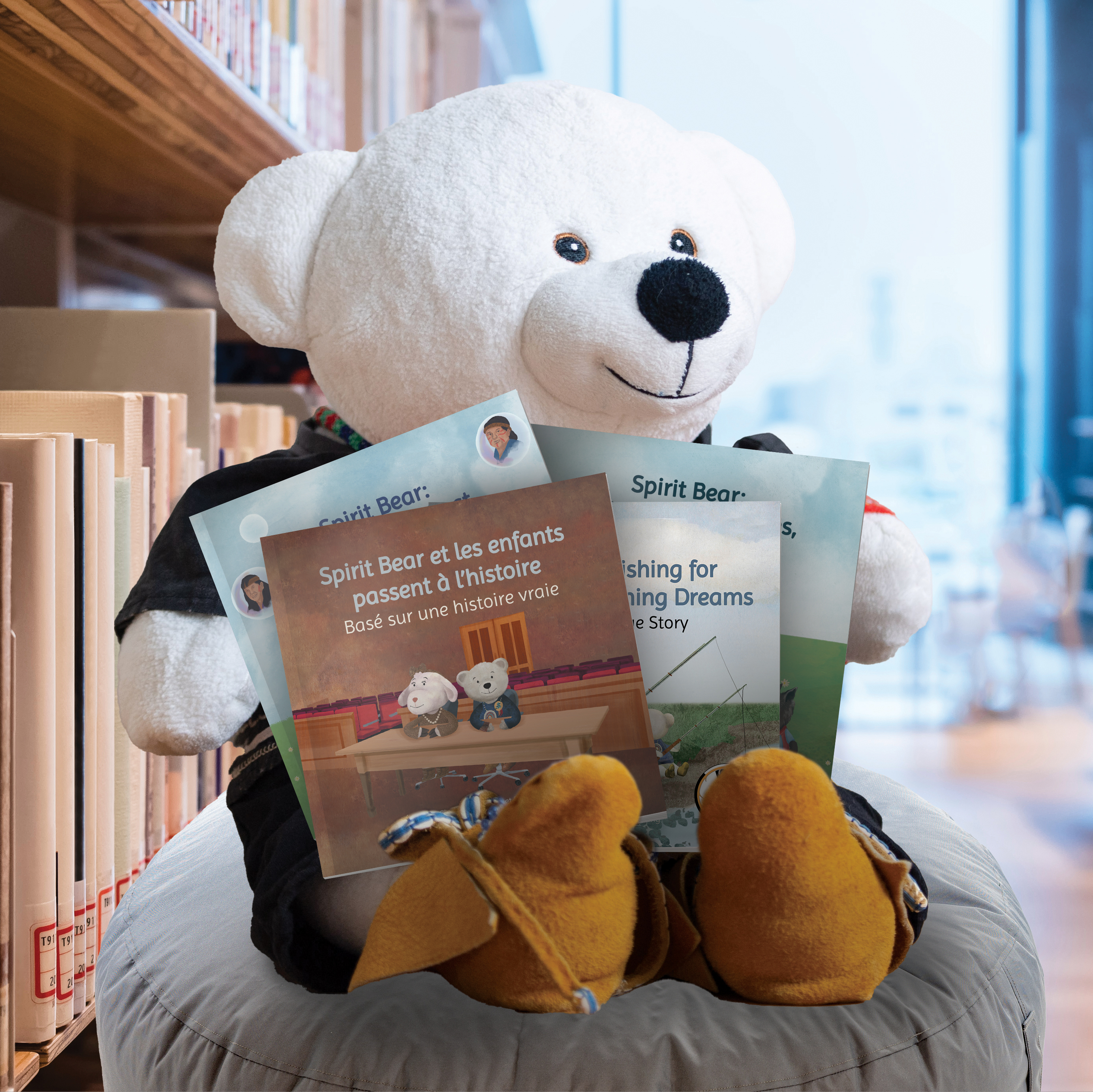 photo of Spirit Bear, sitting on an ottoman in a public library, holding his four books