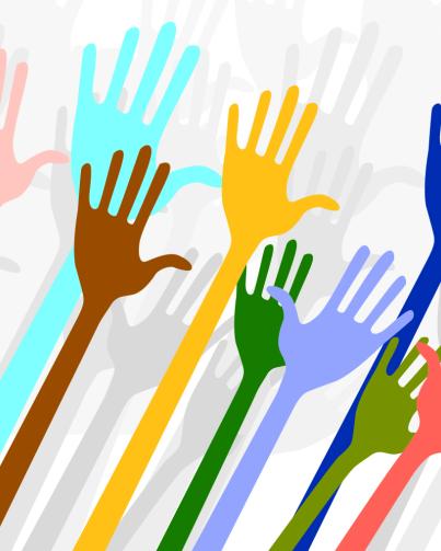 volunteer simple illustration of many different coloured hands being held up in the air, volunteering. The hands in the foreground are all different bright colours. The hands in the background are shades of light grey